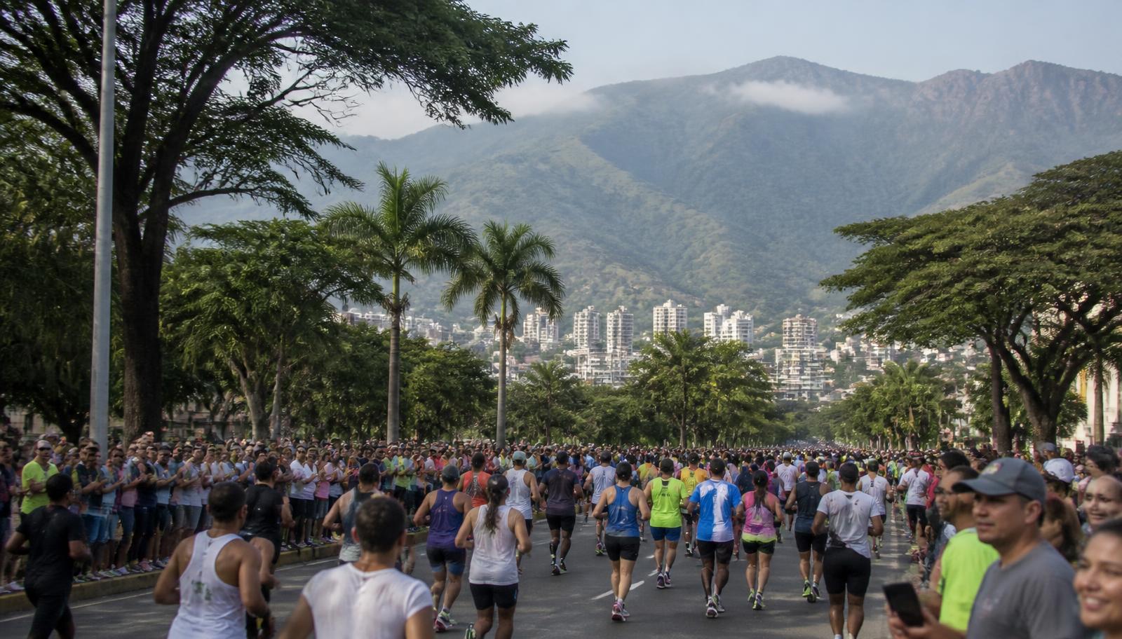 Corredores em avenida arborizada de Cali, na Colômbia, com montanhas dos Andes ao fundo em manhã de neblina